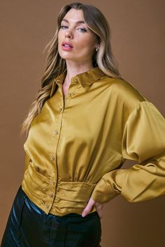 The ROMANTIC MOVES WOVEN TOP is designed to flatter any figure with its wide shirred waist band and classic features like a shirt collar and button down. Crafted from a lightweight fabric, it provides a comfortable fit for a timeless look. DetailsSelf : 100% Polyester Size & Fit- Model is 5`8" And Wearing Size Small- Measurements Taken From Size Small- Approx. Length: 19" Gold Long Sleeve Tops With Button Cuffs, Fitted Gold Top With Button Closure, Gold Long Sleeve Tops With Buttons, Gold Collared Blouse For Fall, Fitted Gold Button-up Blouse, Gold Blouse With Button Closure For Fall, Woven Top, Vintage Inspired Design, Shirt Collar