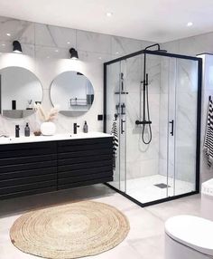 a modern bathroom with black and white decor, round mirrors, and circular rug on the floor