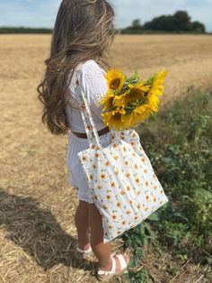 Sunflower Tote Bag - Hand painted fabric design - Handmade to order - Lightweight cotton fabric  - Measures approx 38.5cm x 42.5cm  - Washable  - All items come gift wrapped  SHIPPING Free UK shipping is second class postage. All orders will be made and sent within 7 days of purchase.  Shipping to the USA is standard which can take 1-2 weeks minimum. This is not a tracked service. PLEASE NOTE: Once orders are dispatched with Royal Mail they are out of my control. If there are any issues with receiving items I will be able to send proof of postage which can be used for Royal Mail claims but items are not tracked. © 2021, Handmade by Libby Eco-friendly Summer School Canvas Bag, White Floral Print School Bag, White Floral Print Canvas Bag, Summer Flower-shaped Canvas Bag, Floral Canvas Bag For Daily Use In Summer, Yellow Cotton Canvas Bag For Summer, Summer Floral Print Canvas Bag, White Reusable Shoulder Bag, White Flower-shaped Canvas Bag For Summer