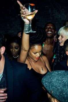 a group of people at a party with one holding up a wine glass in the air