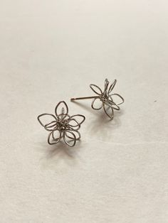 Small metal flower wire stud earrings.  Unique earrings for a unique person. Not intended for children ages 13 and under.   Also, for many items we can accommodate large orders, so please send us a message. Adjustable Wire Wrapped Flower Earrings, Nickel-free Metal Flower Earrings, Nickel-free Flower Shaped Metal Earrings, Whimsical Nickel-free Flower Earrings As Gift, Whimsical Nickel-free Flower Earrings For Gifts, Whimsical Silver Flower Earrings With Ear Wire, Silver Whimsical Flower Earrings, Whimsical Handmade Silver Flower Earrings, Hypoallergenic Metal Flower Earrings