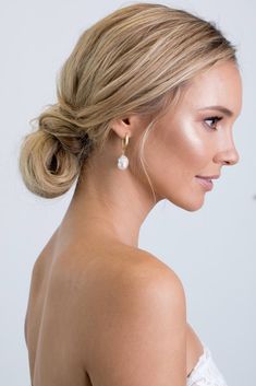 a woman with blonde hair wearing a white dress and pearl earrings, looking off to the side