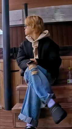 a woman sitting on top of a wooden bench