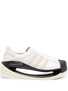 off-white/black calf leather smooth grain panelled design round toe signature 3-Stripes logo perforated detailing contrasting suede heel counter branded insole padded ankle hollow TPU midsole plate rubber outsole front lace-up fastening We've partnered with Good On You — an independent agency that rates how brands perform in relation to their impact on the planet, people and animals, with a multi-criteria rating simplified to a five points scale. In order to be awarded our conscious label, large Japanese Concept, Superstar Shoes, Superstars Shoes, Planet People, Summer Beach Wear, Adidas Superstar Sneaker, Negative Space, Derby Shoes, In The End