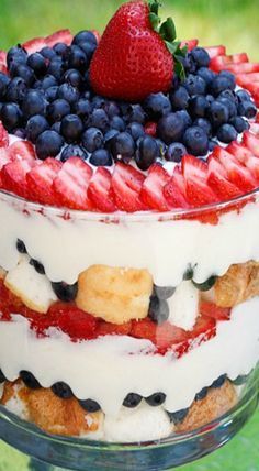 a cake with strawberries and blueberries in it on a glass plate next to a spoon