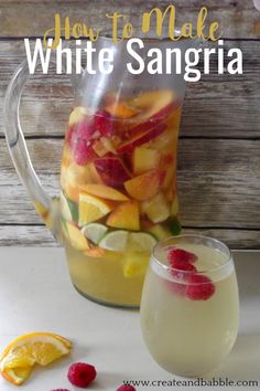 a pitcher full of white sangria next to a glass with raspberries