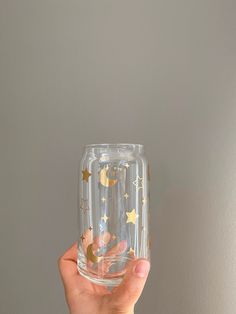 a hand holding up a clear glass with gold stars on it