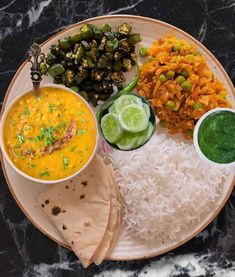 a plate topped with rice, beans and other foods next to green dipping sauces