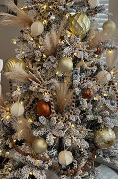 a white christmas tree decorated with gold and silver ornaments