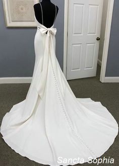 a white wedding dress with a bow on the back