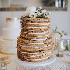 a large stack of cookies with white frosting and flowers sitting on top of it