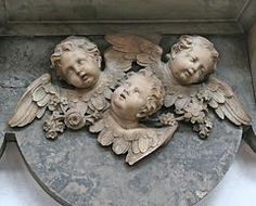 three cherubs with leaves and flowers carved into the side of a building