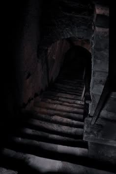 an old set of stairs leading up to a dark room with light coming from the top