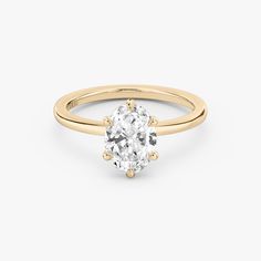 a yellow gold engagement ring with an oval cut diamond in the center, on a white background