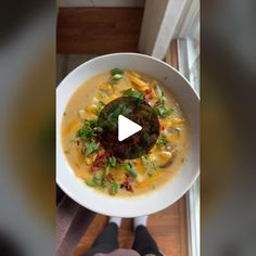 a white bowl filled with soup on top of a wooden floor next to a window