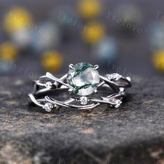 a green and white ring sitting on top of a gray rock with yellow flowers in the background