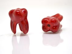 two red gummy bears sitting next to each other on top of a white surface