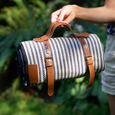 a woman is holding a striped duffel bag