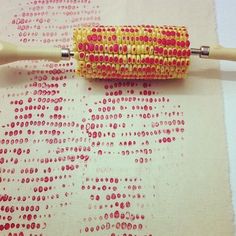 a pair of knitting needles sitting on top of a piece of cloth with red and yellow beads