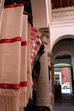 several white and red towels hanging from the ceiling in a building with arches on both sides