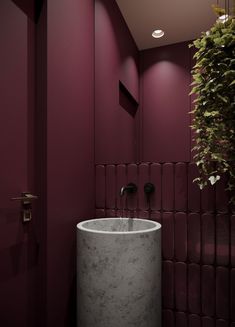 a bathroom with purple walls and a round sink in the middle, surrounded by greenery