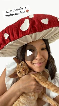 a woman holding a cat in front of a mushroom hat