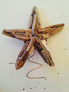 a star made out of driftwood on a white wall with a cord attached to it