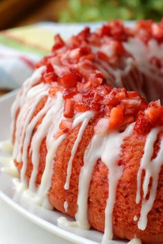 a bundt cake with white icing and strawberry toppings on top, sitting on a plate