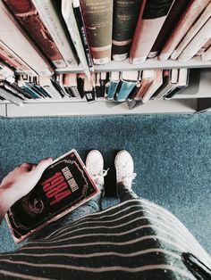 someone is sitting on the floor with their feet up in front of bookshelves