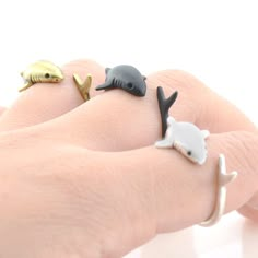 three different types of rings on someone's hand, one with a fish and the other with a shark