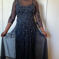 a woman in a long black dress with sheer sleeves and an embellished top