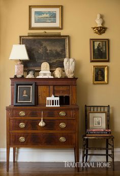 an antique dresser in the corner of a room with pictures on the wall above it