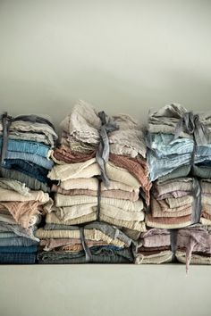 a stack of folded clothes sitting on top of a white table next to a wall