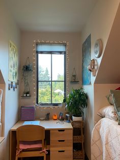 a bedroom with a bed, desk and window in it's corner area that has string lights on the windowsill