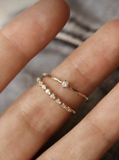 a woman's hand with two gold rings on top of her finger and one in the middle