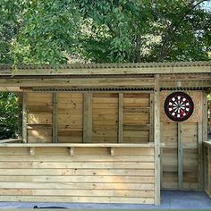 an outdoor bar with a dart on the back wall and darts in the front door