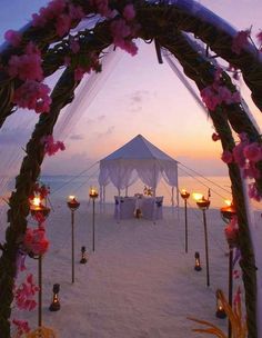 an image of a wedding on the beach with candles and flowers in the foreground