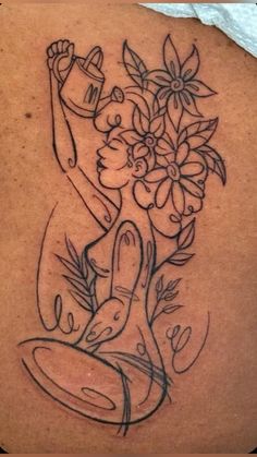 the back of a woman's shoulder with flowers and a buddha tattoo on it