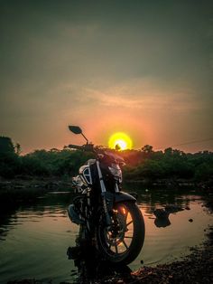 a motorcycle is parked in the water at sunset