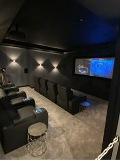 a home theater with black leather seats and blue lights on the wall, along with two stools