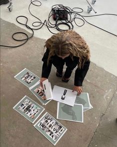 a person kneeling down on the ground looking at some pictures with their hands over them