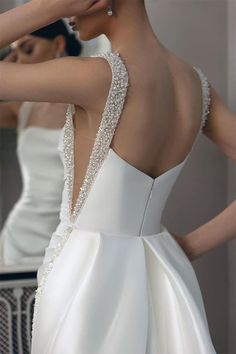 the back of a woman's white wedding dress with beading on her shoulders