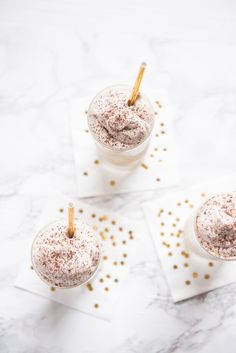 three desserts with gold sprinkles on top of each one in small cups