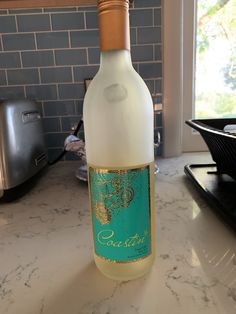 a bottle of white wine sitting on top of a counter next to a toaster