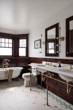 a bathroom with two sinks, a toilet and a bathtub in the middle of it