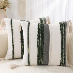 two pillows with tassels on them sitting on a couch