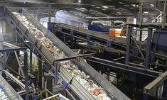 a conveyor belt in a factory filled with trash and other things that are being processed