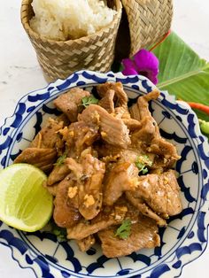 a blue and white plate topped with meat next to rice