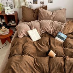 an unmade bed with brown sheets and books on the pillowcase in front of it