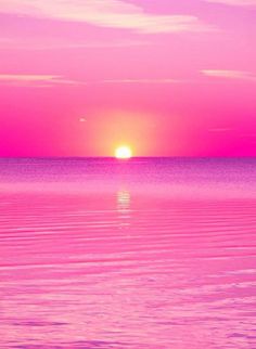 the sun is setting over the ocean with pink and purple hues in the sky